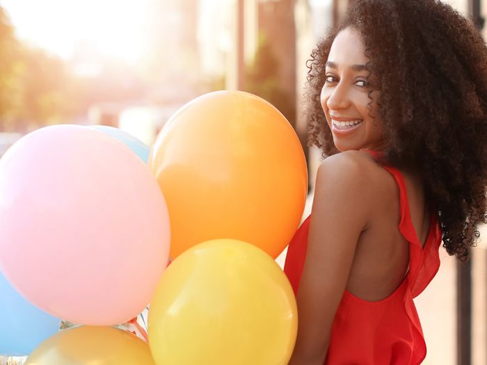 girl smiling and standing next to some balloons