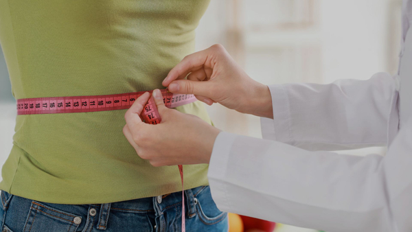 medical professional measuring weight loss from womans waist