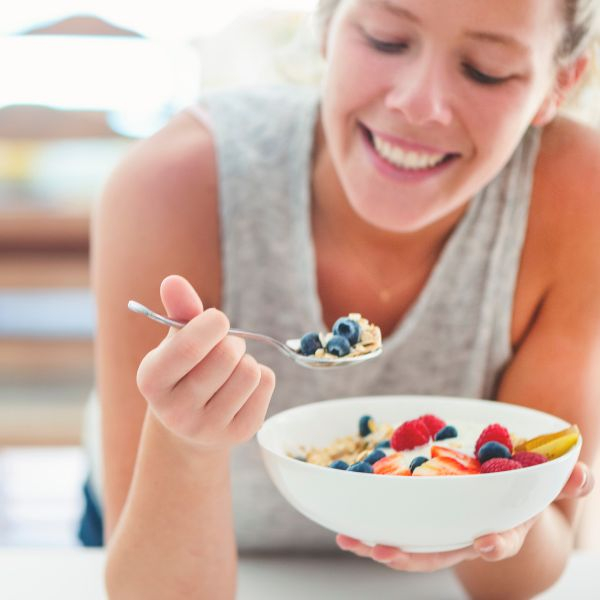 woman eating a bowl of fruit and yogurt