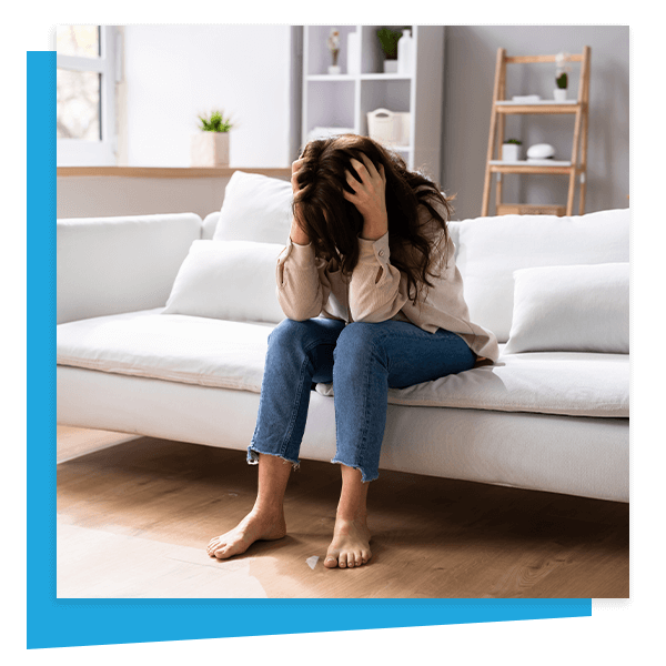 woman in distress on couch with hands on her head