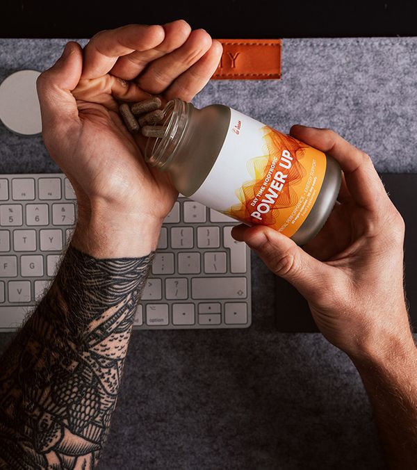 A tattooed person pouring supplements into his hands