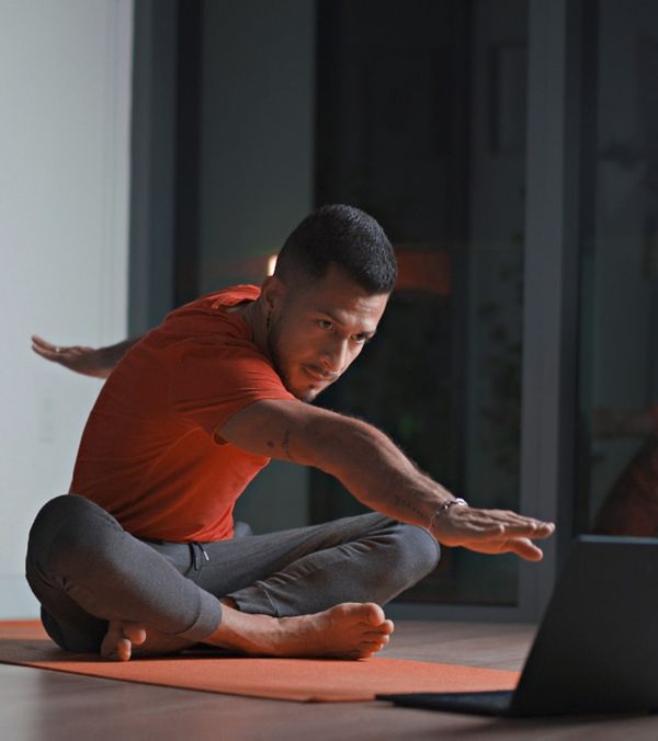 A man at home doing a workout in front of his laptop