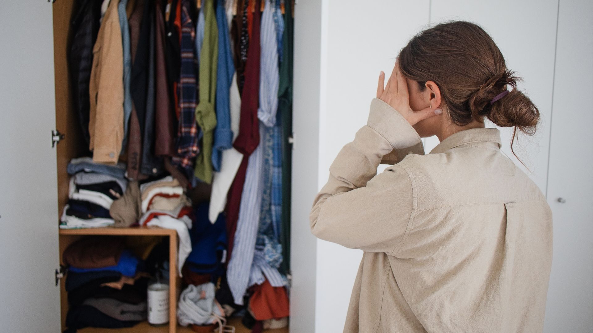Woman stressed looking into her cluttered closet