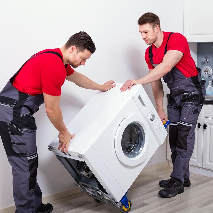Two men moving a washing machine on a dolly