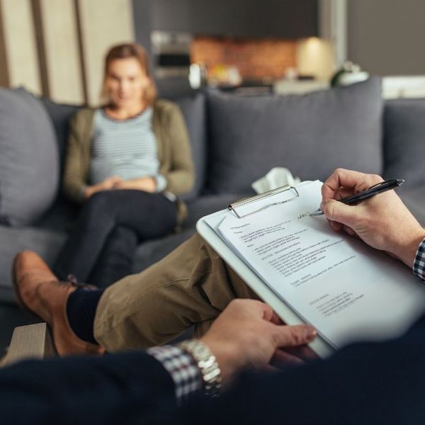 a woman on a couch talking with a man taking notes