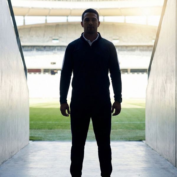 Silhouette of a confident coach standing in a stadium tunnel representing strong leadership.