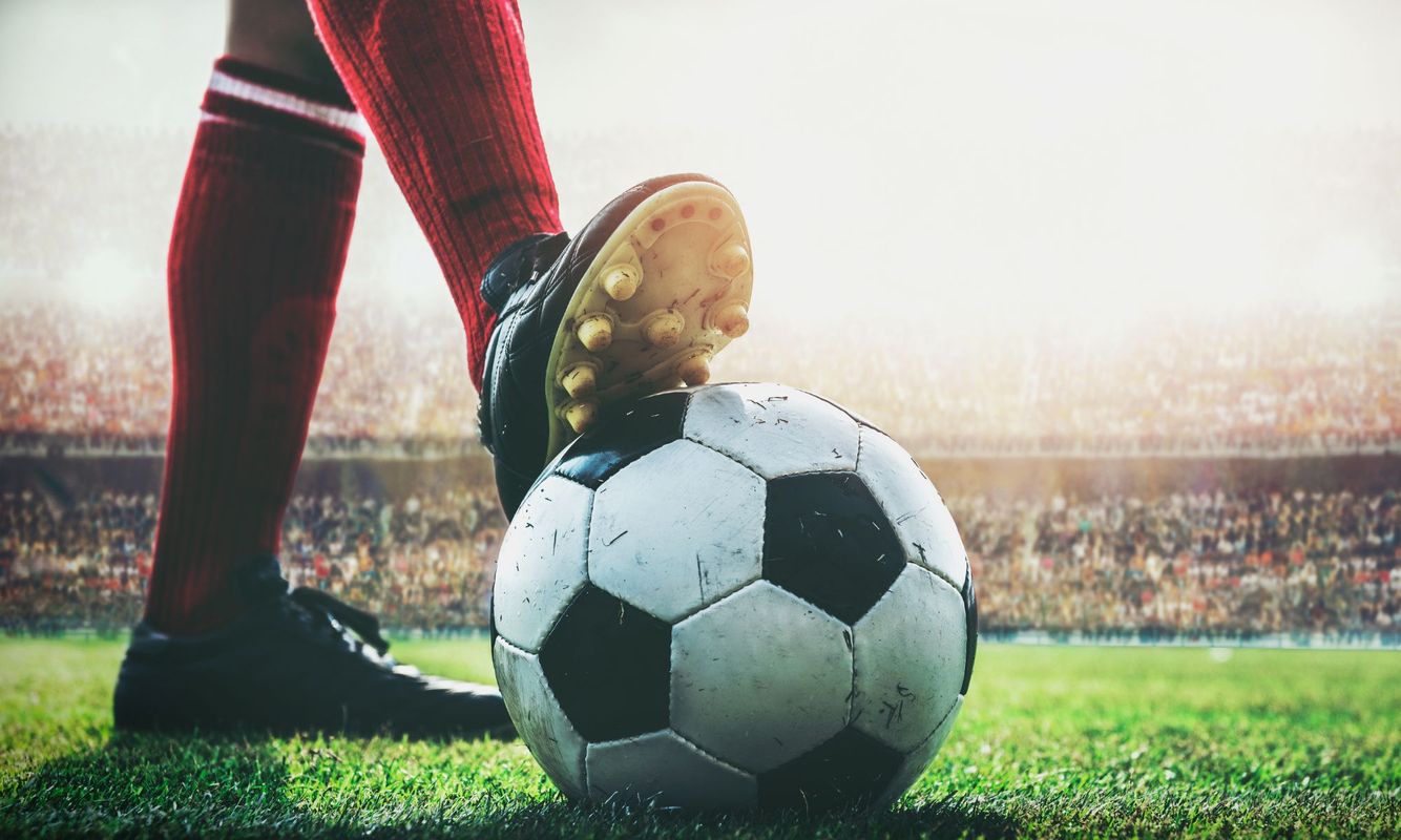 a person holding a soccer ball under their foot in a stadium