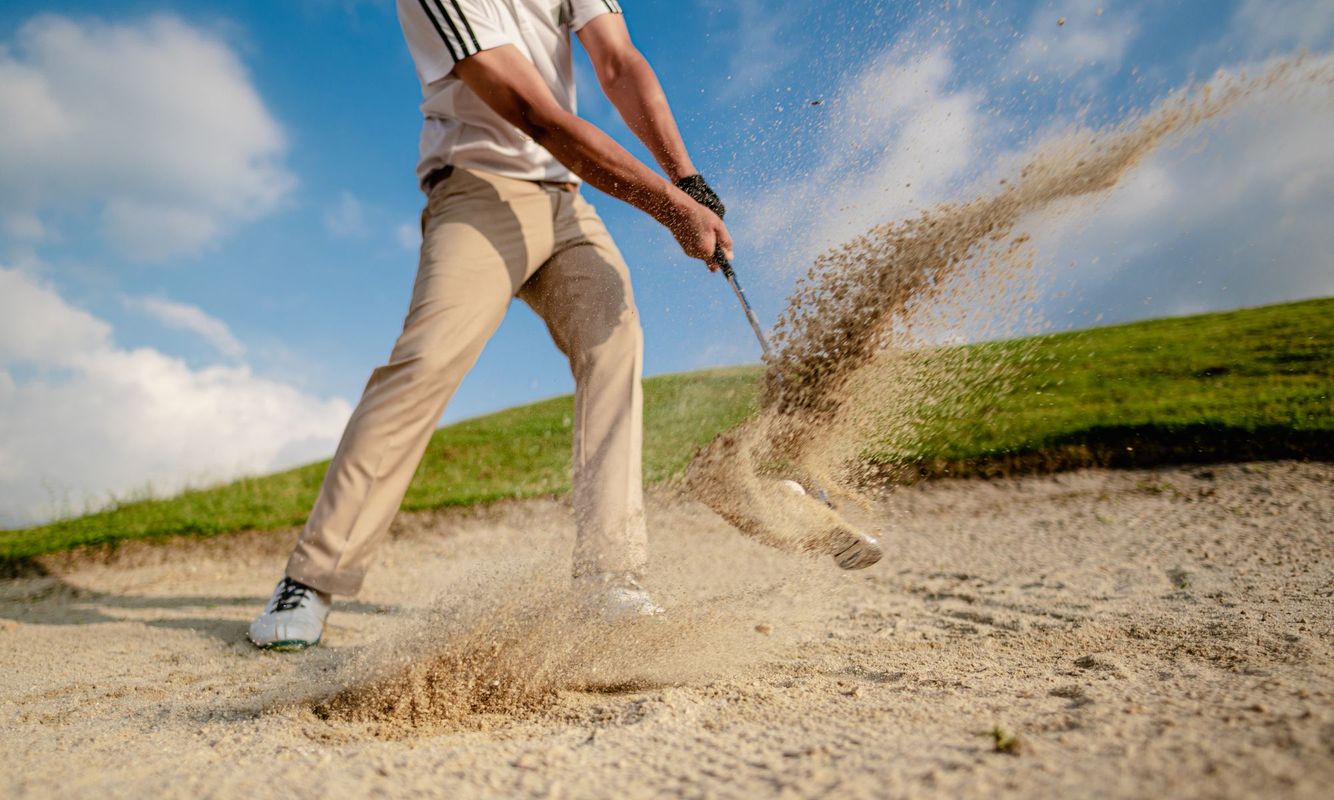 a golfer whacking a ball out of a sand trap