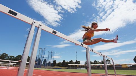 woman running and jumping over a hurdle woman running and jumping over a hurdle