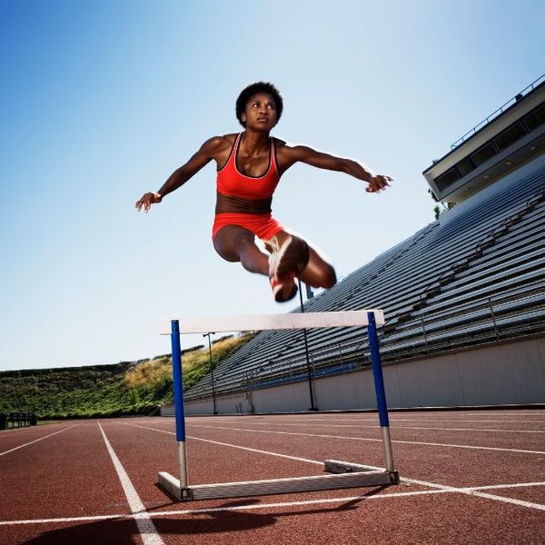 a woman jumping over a hurdle