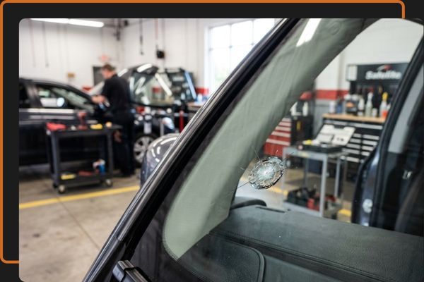 Close-up of a certified Kootenay Glass technician carefully repairing a rock chip on a car windshield in a clean auto bay.