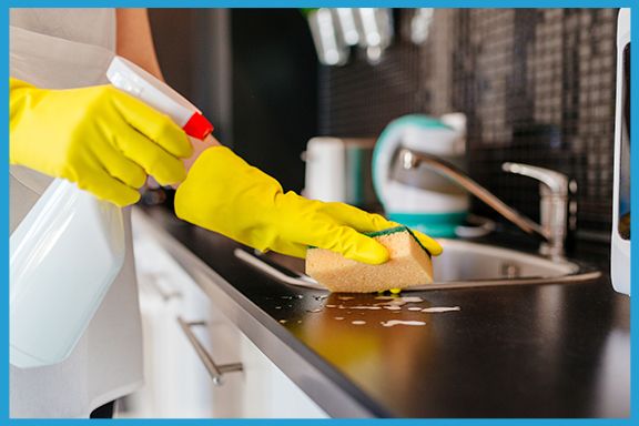 Image of a person cleaning a counter with a sponge