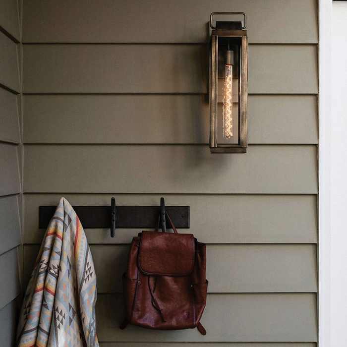 Tall, rectangular antique brass outdoor wall lantern with a long vintage Edison filament bulb, mounted on olive green horizontal siding.