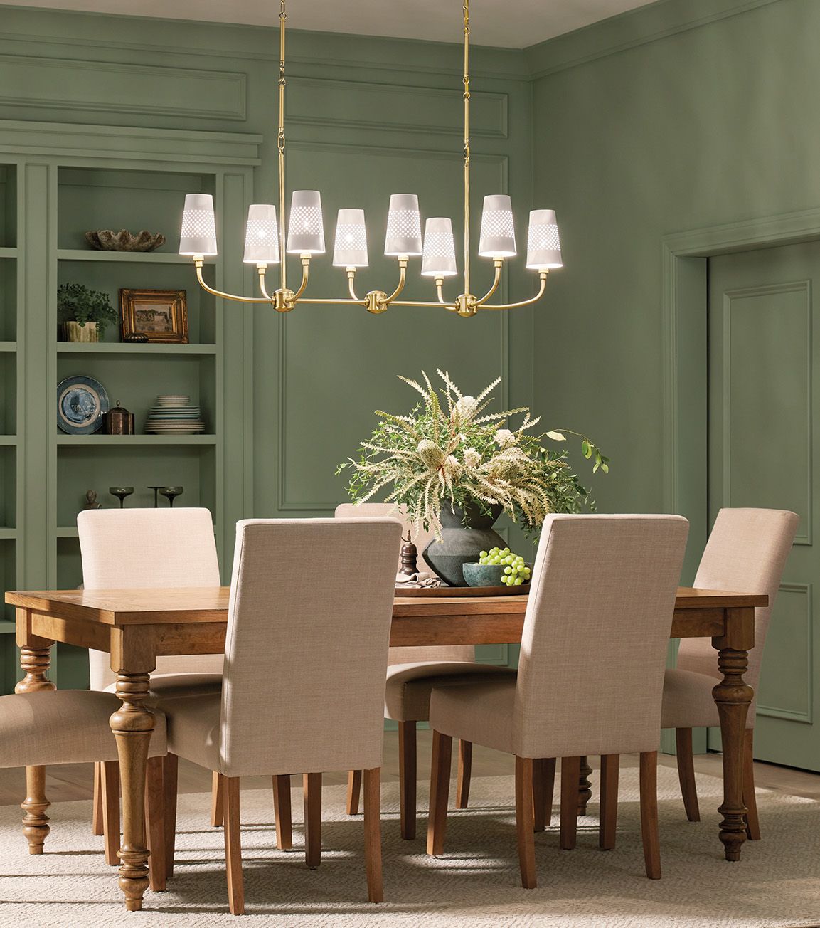green dining room with gold chandelier