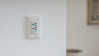 White wall-mounted Kichler light and fan remote control. White wall-mounted Kichler light and fan remote control.