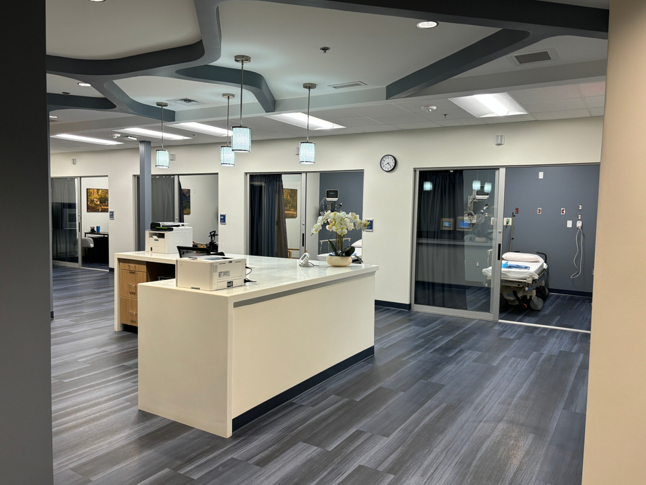 A bright, modern nursing station and recovery area inside the Southern Kentucky Vascular clinic featuring glass-enclosed patient procedure rooms.