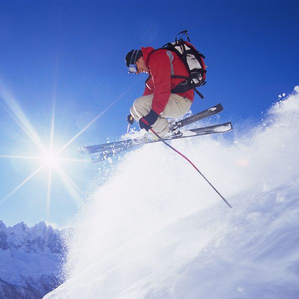 A man on skis jumping in the air as he moves down a mountain.