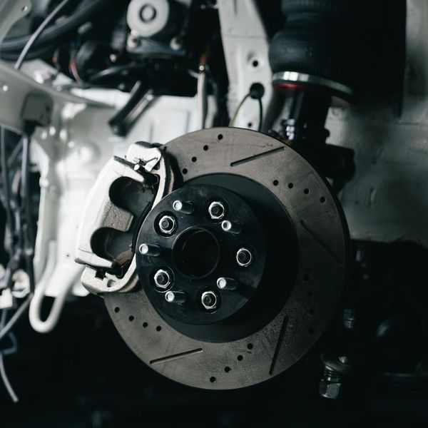A close-up of a high-performance disc brake assembly with a new brake pad being installed by a mechanic.