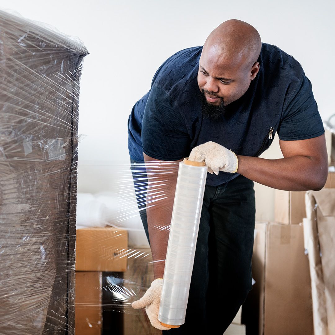 A professional mover shrink wrapping a specialty item 