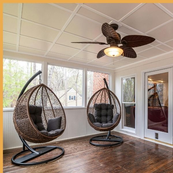 Tropical leaf ceiling fan with light installed in a sunroom with egg hanging chairs