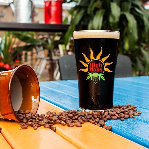 a pint of dark beer with coffee beans on a table