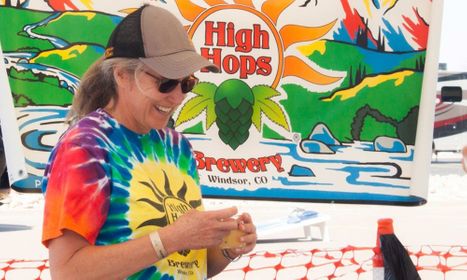 a woman in tie dye in front of a High Hops Brewery Banner