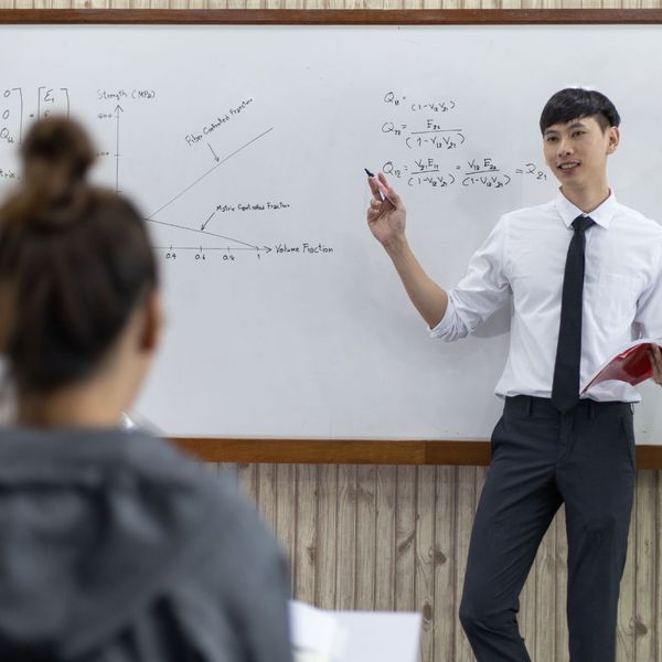 Teacher explaining equations on whiteboard to student