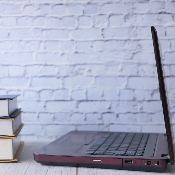 Partially open laptop beside stacked books