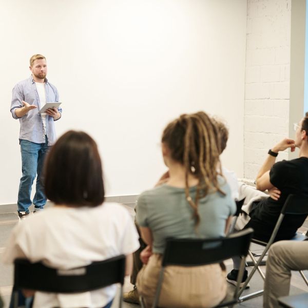 Man presenting to seated group with tablet