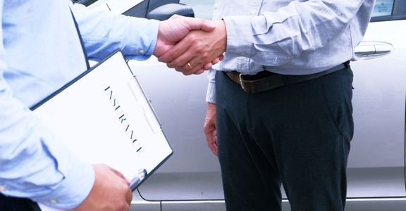 Handshake next to car, clipboard labeled "Insurance."