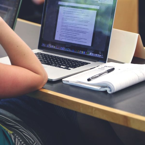 Person working on laptop with notebook nearby