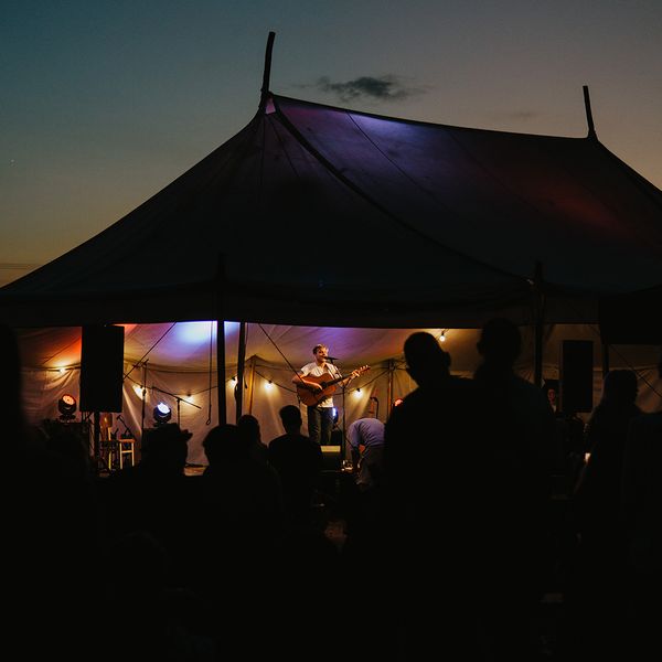 a crowd of people listening to live music under a tent