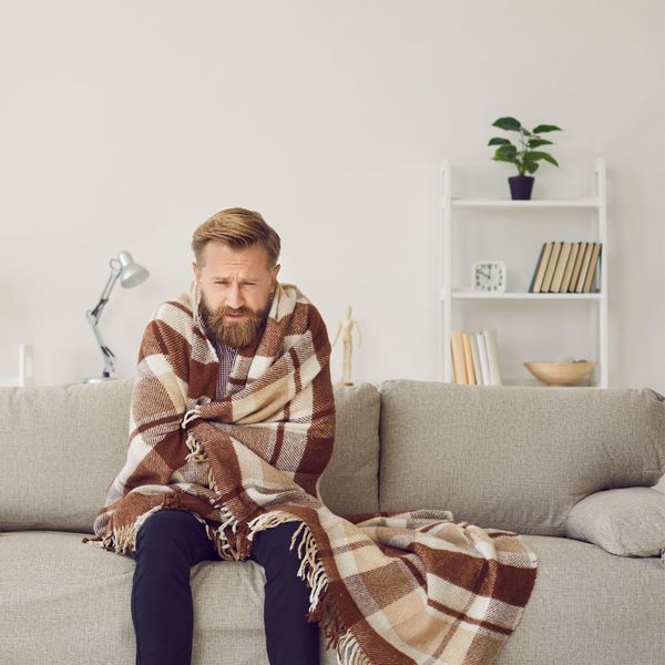 Man cold with a blanket on in house