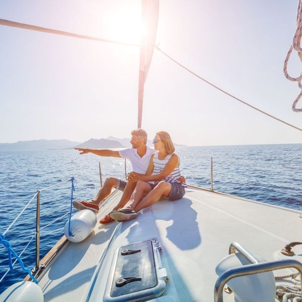 A couple sitting on the bow of a yacht.