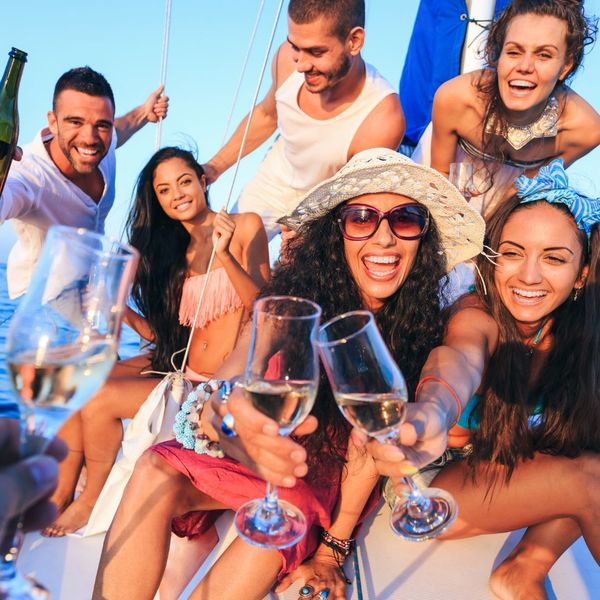 a large group of people posing and cheering in a photo on a yacht