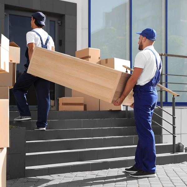two movers carrying a large box up stairs