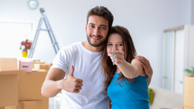 Couple holds keys to new home in unpacked living room