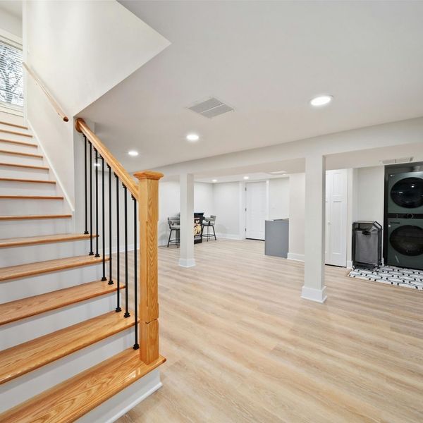 a finished basement space with hardwood floors and laundry room