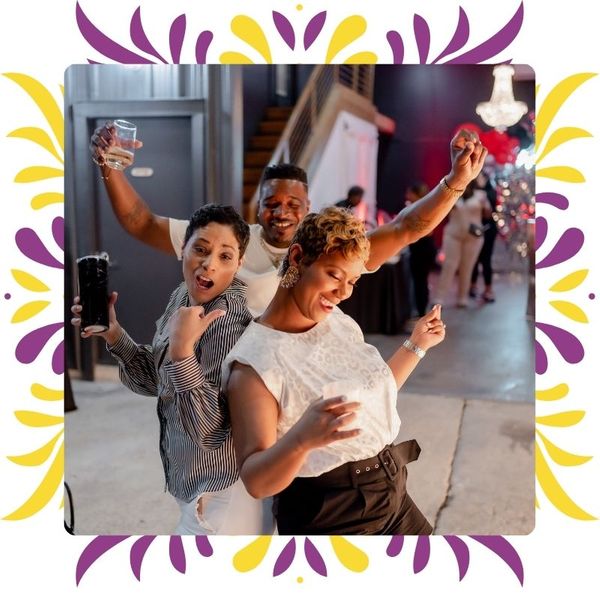 Three colleagues dancing and cheering in the indoor private party space