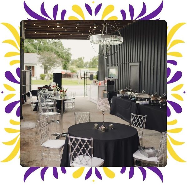 Elegant black and white buffet setup with crystal lighting and clear chiavari chairs inside the covered industrial area of NOLA Station