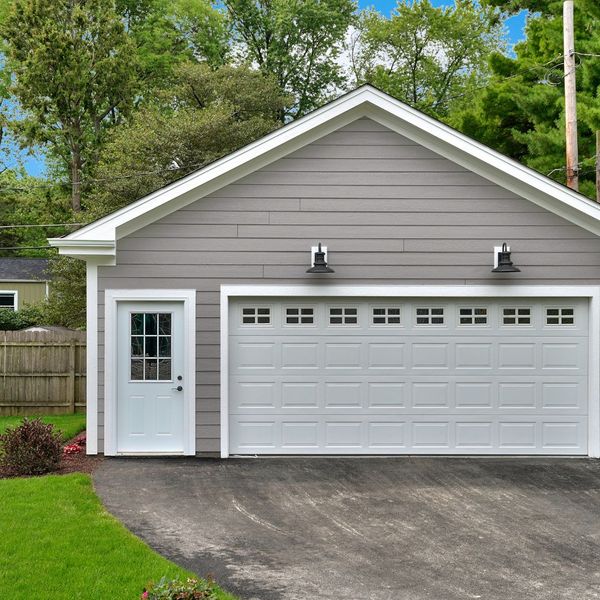 A detached brown garage with a white door and garage door