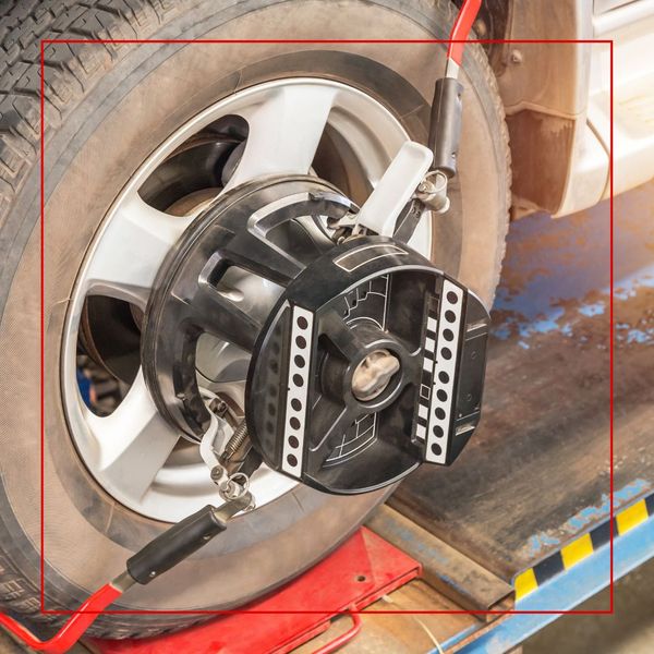 A close-up of a wheel alignment sensor mounted on a car's tire, with the tire resting on an alignment rack. A close-up of a wheel alignment sensor mounted on a car's tire, with the tire resting on an alignment rack.