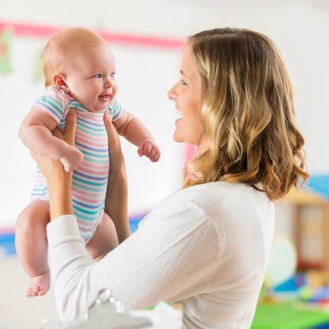 Woman happily holding up an infant. 