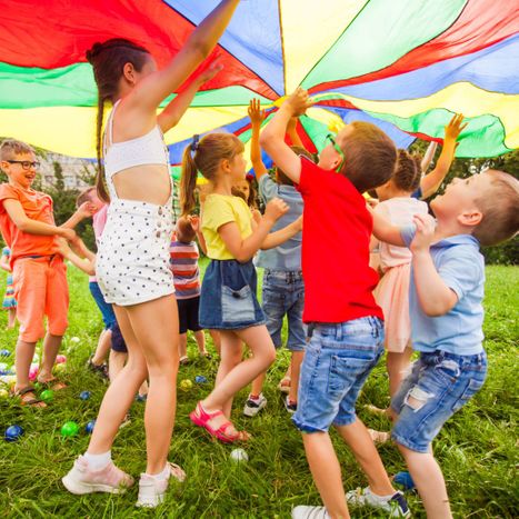 Kids playing an outdoor game with a parachute. 