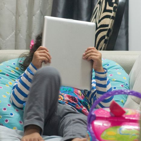Kid blocking her face with a tablet