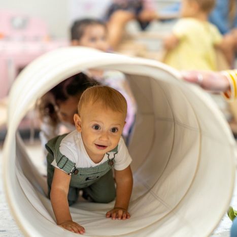 infant crawling through a play tunnel. 