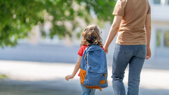 mom walking daughter into preschool
