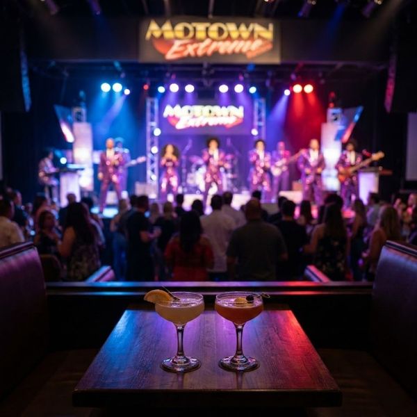 Perspective from a private booth looking past cocktails toward a blurred live stage performance at the Motown Extreme Bar