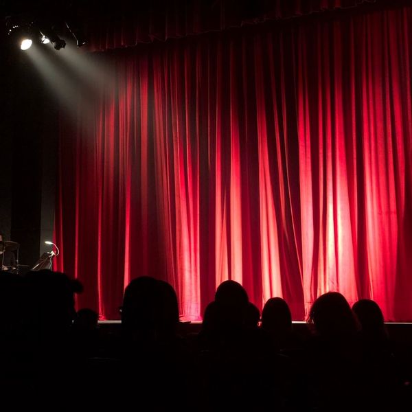 a crowd in front of a red curtain with a spotlight shining on it