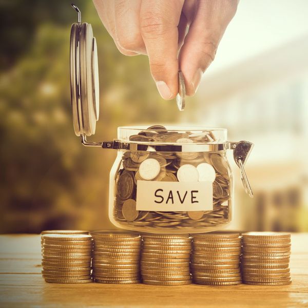 A hand putting a coin in a jar labeled "save"